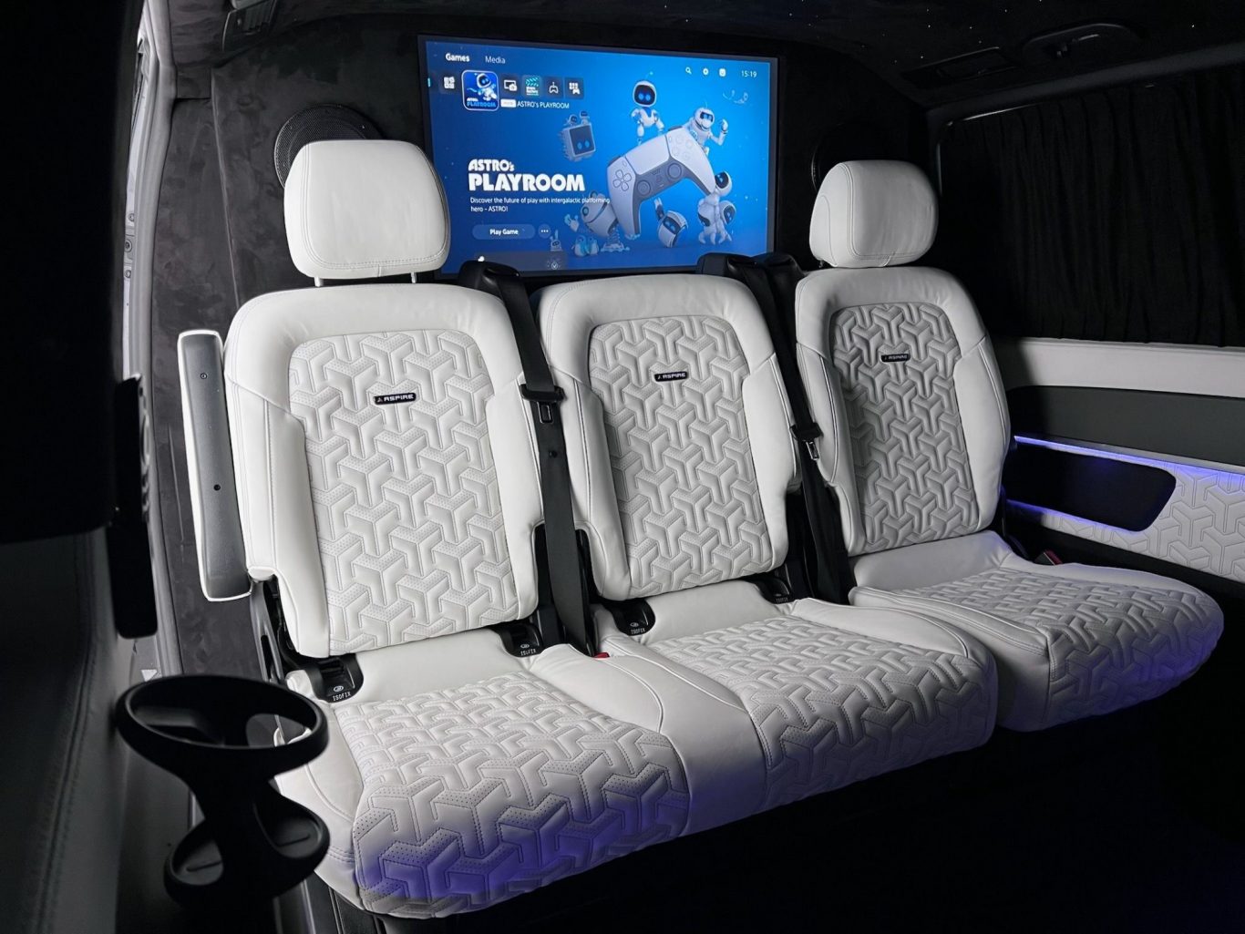 White three-seater with headrests and a screen in a modern vehicle interior.