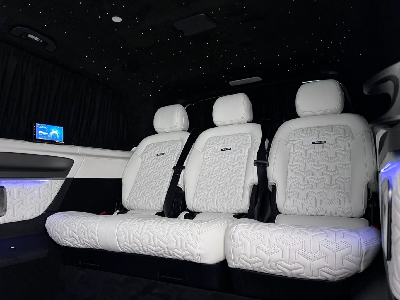 Luxury car interior featuring three plush white seats and starry ceiling lighting.